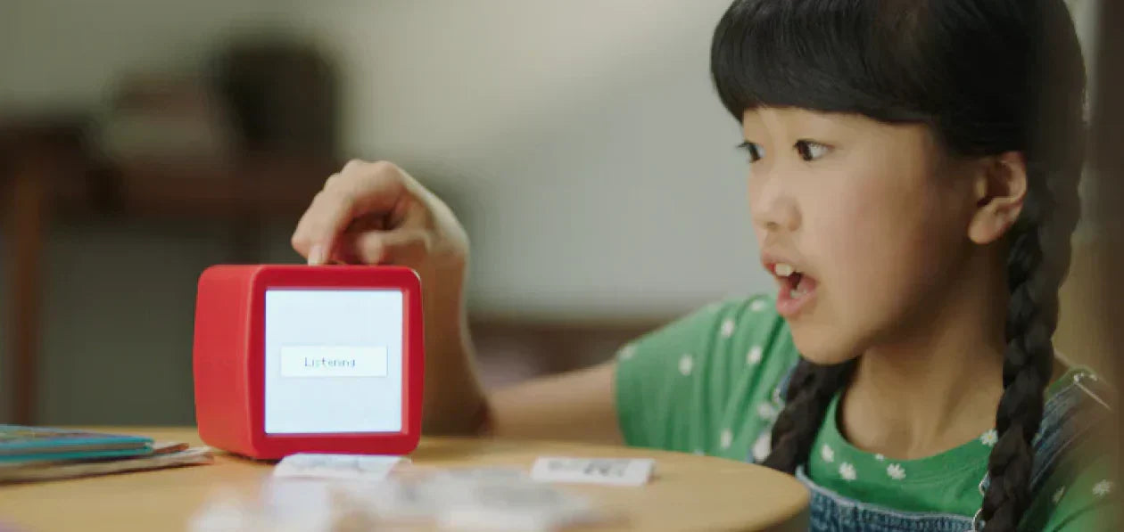 A child speaking into Stickerbox printer, and the Stickerbox is showing "Listening" on its screen.