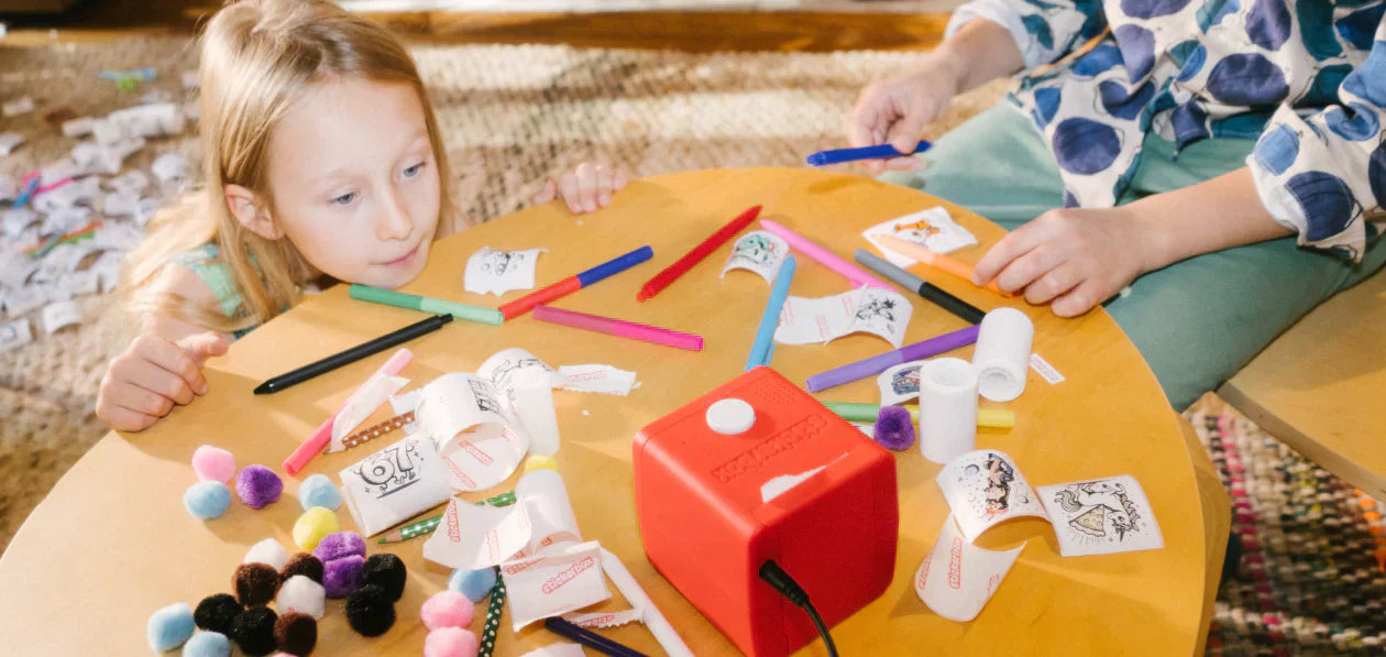 a girl coloring stickers with another girl looking at Stickerbox