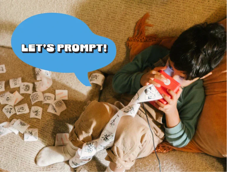 A child holding and talking into Stickerbox. There is a text next to him that says "Let's Prompt!" 