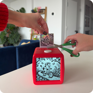 An adult using a pair of kid-safe scissors to cut holographic stickers.